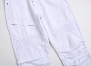 Gros plan d'un pantalon de motard blanc avec genoux plissés et coutures renforcées