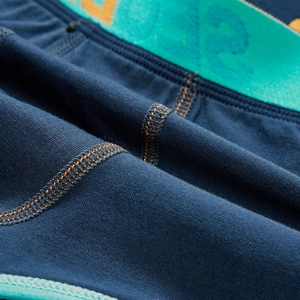 Macro shot of men's trunks with contrast orange stitching and cyan elastic waistband