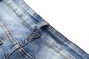 Detailed macro shot of light blue denim jeans showing contrast orange stitching and texture