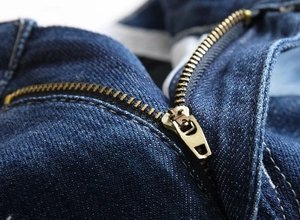 Close-up of durable bronze metal zipper on dark blue denim straight leg casual shorts