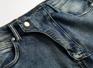Vue macro détaillée de la taille d'un jean bleu rétro avec bouton doré et rivets en métal