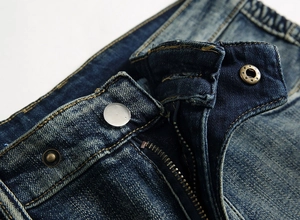 Détails macro de la taille d'un jean bleu foncé avec bouton en métal et coutures jaunes