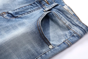 Close-up of light blue denim fabric with orange stitching and size 32 label detail