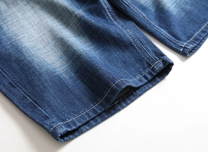 Detailed close-up of blue washed denim hem with high-quality double stitching detail