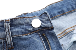 Detailed close-up of blue denim waist with silver button and orange stitching