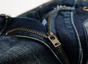 Détail macro de la fermeture éclair en métal et coutures durables sur jean bleu vintage