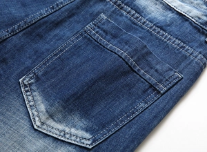 Detailed close-up of dark blue denim jeans with back pocket and reinforced stitching