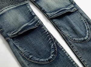 Gros plan d'un jean bleu foncé avec panneaux plissés style motard et coutures renforcées