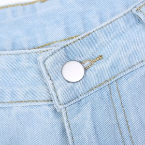 Detailed close-up of blue denim jeans waist with silver button and yellow contrast stitching