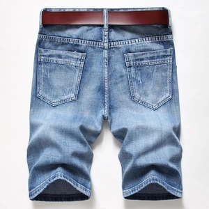 Close-up of light blue washed denim shorts featuring back pockets and vintage distressed details
