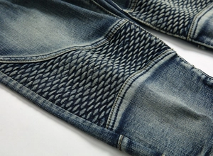 Détail d'un jean biker vintage bleu foncé avec des empiècements plissés aux genoux