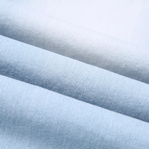 Macro detail of light blue denim fabric texture with clear twill weave pattern and soft folds