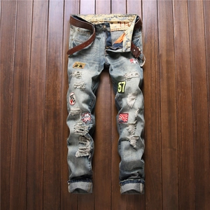 Men's straight distressed jeans with vintage patches and belt on wood background