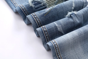Detailed macro view of distressed blue denim fabric with vintage frayed holes and textures