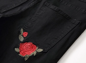 Men's slim fit black ripped jeans featuring red rose embroidery detail on the back pocket