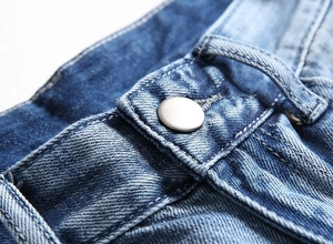 Macro detail of men's casual blue denim shorts showing metal button and belt loops