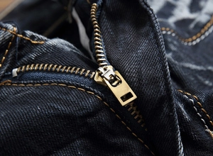 Gros plan détaillé sur la fermeture éclair en laiton du jean denim effet vieilli