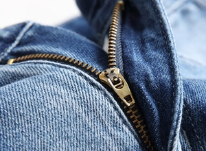 Macro detail of high-quality metal zipper and vintage washed denim texture on men's jeans