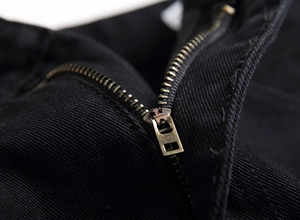 Vue macro d'une fermeture éclair en bronze sur un pantalon de moto en sergé noir de qualité