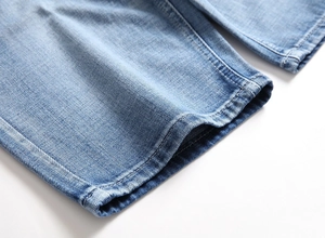 Detailed macro view of light blue denim fabric hem featuring durable double-stitch seams