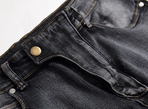Détail du denim noir délavé avec bouton en bronze et surpiqûres jaunes