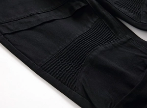 Gros plan du jean biker noir avec empiècements plissés et coutures renforcées