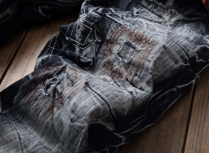 Gros plan d'un jean gris pour homme délavé avec détails déchirés et coutures contrastées