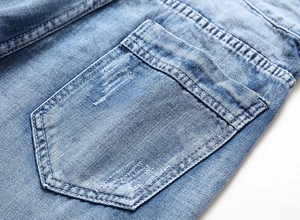 Detailed macro of light blue denim pocket with double stitching and vintage distressed texture