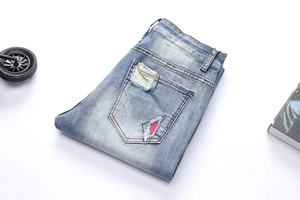 Close-up of denim jeans back pocket with distressed details and a red triangular patch