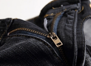 Détail d'une fermeture éclair en laiton vintage sur un jean en denim noir épais