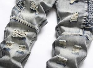 Detailed close-up of blue distressed jeans with ripped holes and side wave pattern texture