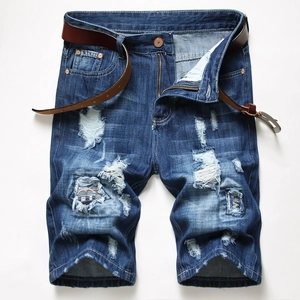 Detail view of men's blue distressed denim shorts with ethnic woven patches and brown belt