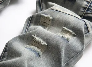 Close-up of distressed light blue denim jeans with parallel ripped holes and frayed edges