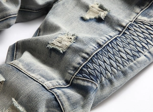 Detailed macro view of distressed denim fabric with ripped texture and pleated stitching