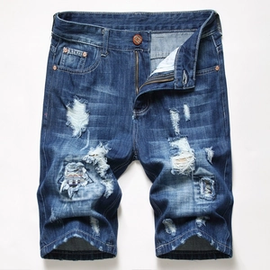 Close-up of men's distressed denim shorts with ethnic woven patches and bronze buttons