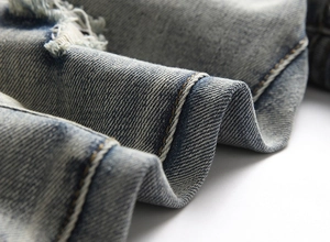 Detailed macro view of distressed denim fabric with blue wash and yellow stitching