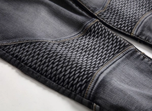 Gros plan d'un jean moto gris anthracite avec genoux plissés et surpiqûres dorées contrastées