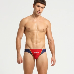 Détail du slip de bain homme avec panneaux latéraux rouges et bleu marine géométriques