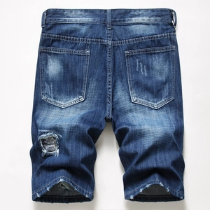 Detail of distressed denim shorts showing vintage patch and frayed hems in navy blue