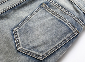 Detailed view of light blue washed denim back pocket with vintage distressed texture