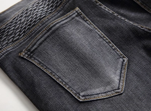 Détail du jean gris délavé avec plis surpiqués style motard et design de poche arrière
