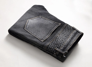Détail d'un jean biker gris foncé avec délavage vintage et plis nervurés aux genoux