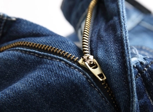 Detailed macro view of heavy-duty brass zipper on premium dark blue denim jeans