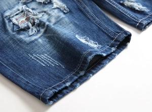 Detailed close-up of blue denim jeans with distressed holes and a star-shaped patchwork