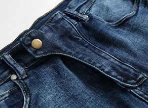 Détail de la taille d'un jean bleu foncé avec bouton en laiton et rivets en métal