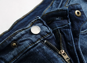 Détail d'un jean en denim avec boutons à motif étoile et fermeture éclair en bronze