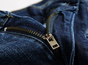 Vue macro d'un jean en denim bleu marine de qualité avec détail de fermeture éclair en bronze
