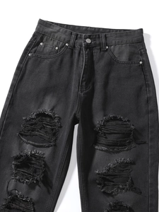 Nahaufnahme der Distressed-Denim-Textur mit Riss-Fransen an schwarzer High-Waist-Jeans