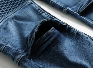 Détail de jean denim bleu foncé avec coutures plissées style motard et poche visible
