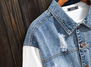 Close-up of blue denim jacket with white knit sleeves and branded neck label detail